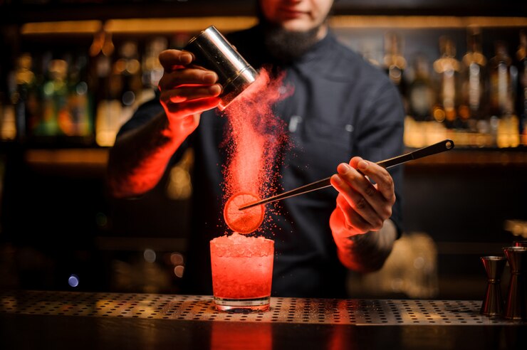 Barman aggiungendo spezie in polvere in un bicchiere da cocktail con una fetta di limone