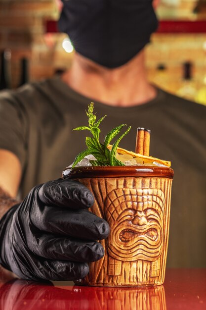 Barman che dà cocktail Tiki al bar.