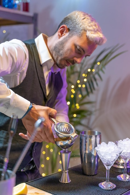 Barman che prepara cocktail mojito nel night club aggiungendo ingredienti e creando drink esperti al bar