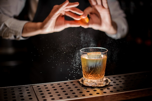 Barman che produce un gustoso cocktail estivo vecchio stile con succo d'arancia