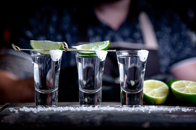 Barman che versa lo spirito duro in piccoli bicchieri come colpi alcolici di tequila o bevanda forte.