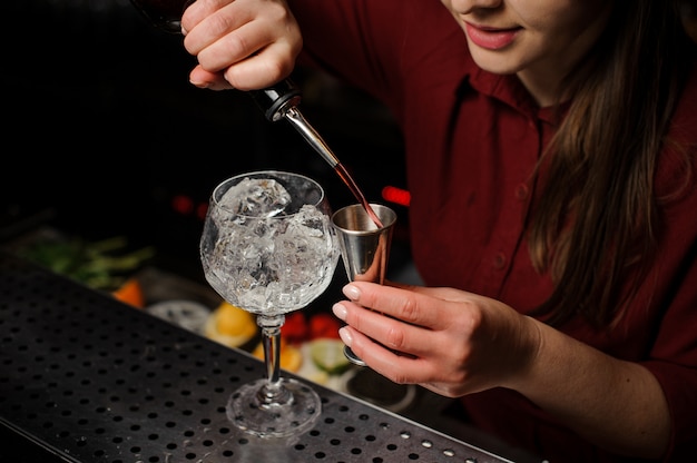 Barman donna che versa amaro per preparare un cocktail con siringa Aperol