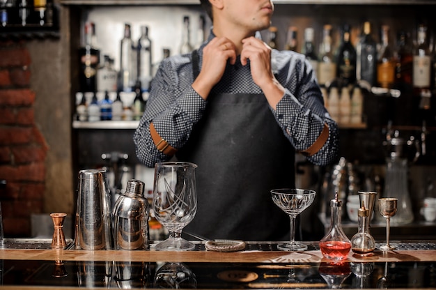 Barman in piedi dietro il bancone del bar con un'attrezzatura da bar