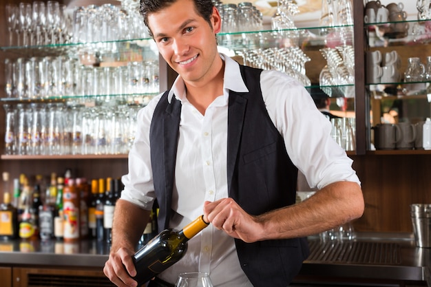 Barman in piedi dietro la barra con il vino