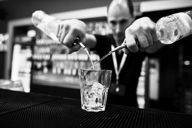 Barman tenere bottiglia e versando cocktail al bar