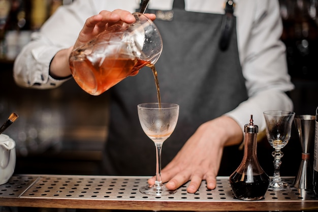 Barman versando fresca bevanda alcolica nel bicchiere da cocktail