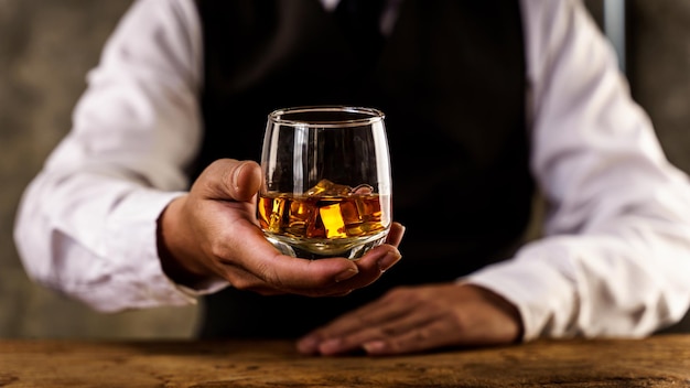 Barman versando il bicchiere di whisky di whisky e dando