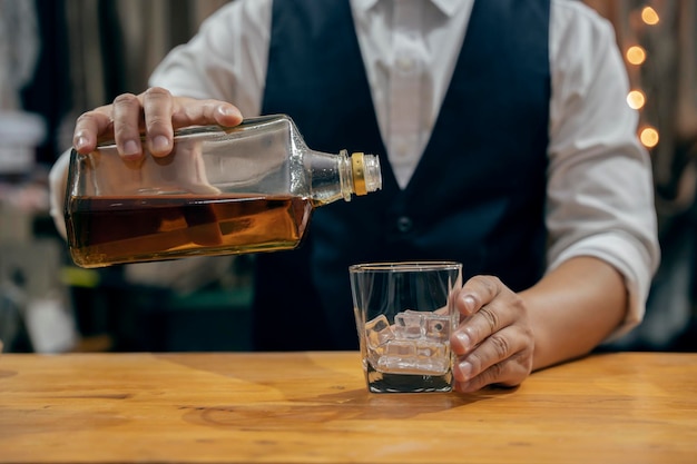 Barman versando whisky bicchiere di whisky bella notte