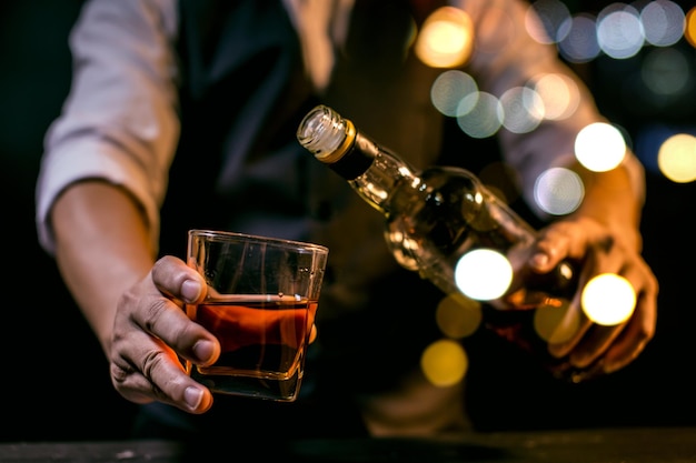 Barman versando whisky bicchiere di whisky bella notte