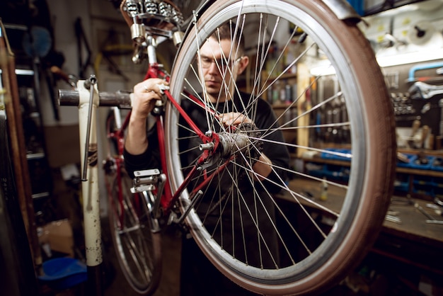 Barra posteriore professionale della bicicletta di pulizia del giovane nell'officina.