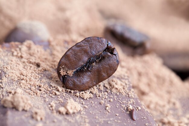 Barretta di cioccolato con copertura in polvere di cacao e chicchi di caffè, primo piano di cibo al cacao, foto con ingredienti per il tempo libero-cacao e caffè