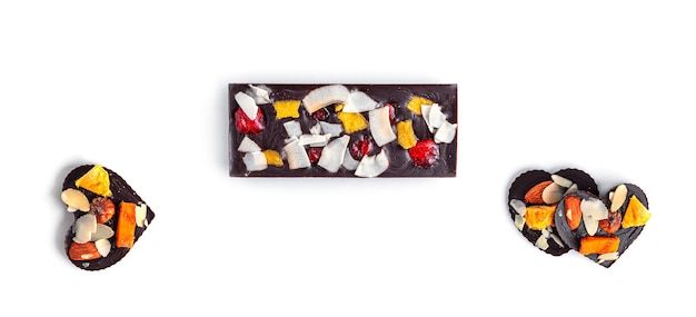 Barretta di cioccolato crudo con frutta secca e noci su sfondo bianco