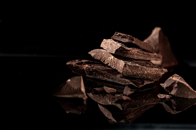 Barrette rotte di cioccolato fondente su uno sfondo scuro