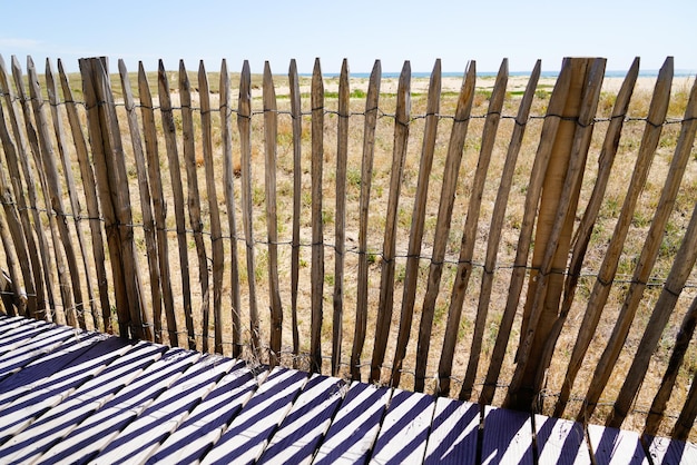 Barriera protettiva in legno della duna che conduce alla passerella di accesso al mare sulla spiaggia sull'orizzonte dell'Oceano Atlantico a Jard sur Mer in Francia