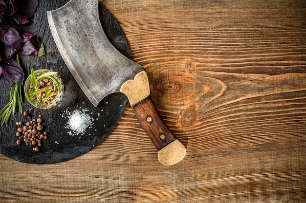 Basilico e un rametto di rosmarino con ascia per carne su fondo di legno vista dall'alto