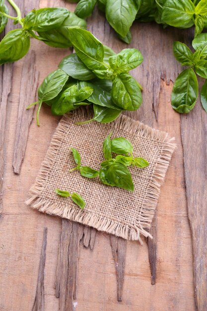 Basilico fresco verde con tela di sacco sul tavolo da vicino