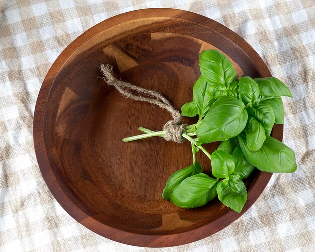 Basilico fresco verde in piatto di legno sui precedenti rustici