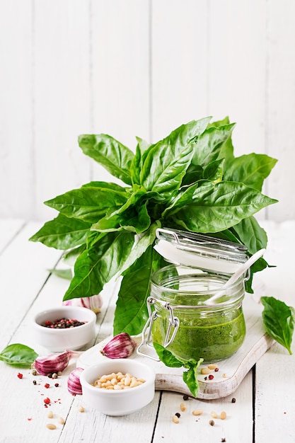 Basilico, pinoli ed aglio freschi casalinghi della salsa di pesto su fondo di legno bianco. Cibo italiano.