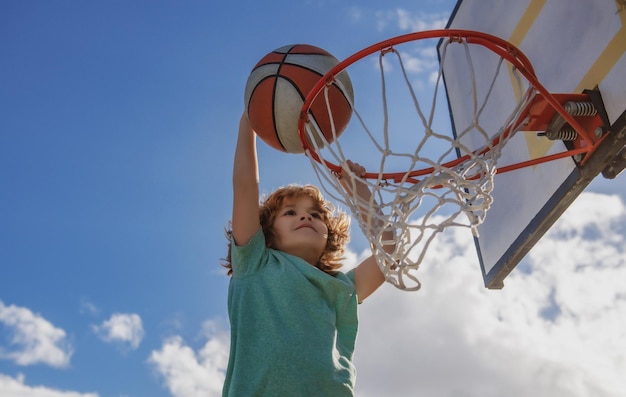 Basket bambini gioco carino bambino ragazzo che tiene una palla da basket cercando di fare un punteggio all'aperto sul gioco