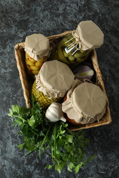 Basket with pickled food and ingredients on black smokey