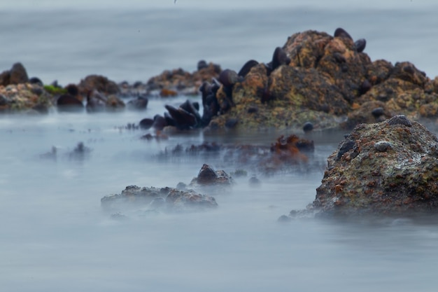 Bassa velocità dell'otturatore fotografare l'acqua che circonda la formazione rocciosa in Namibia, Africa al tramonto nell'Oceano Atlantico