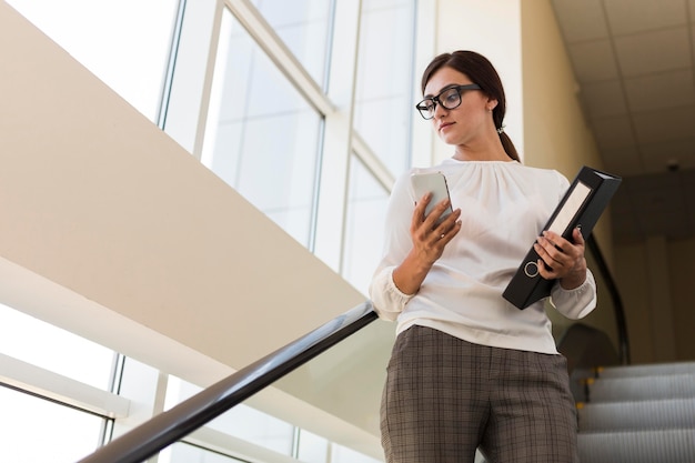 Basso angolo di imprenditrice azienda legante e lavorando su smartphone