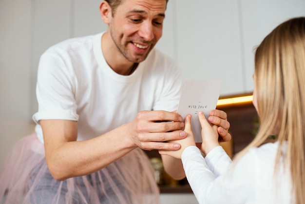 Basso angolo di ragazza che dà una carta per la festa del papà a suo padre