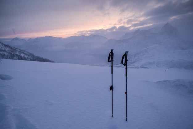 Bastoncini da trekking dello scalatore sulla collina nevosa nella bufera di neve