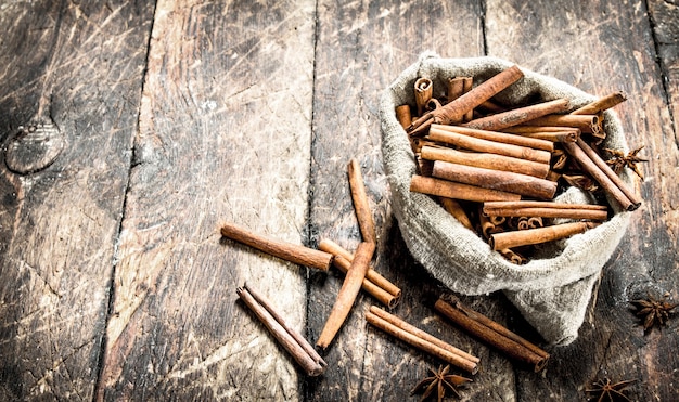 Bastoncini di cannella in una vecchia borsa sulla tavola di legno.