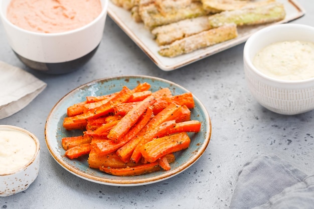 Bastoncini di carote al forno con salsa e hummus su un tavolo da pranzo Cibo vegetariano sano