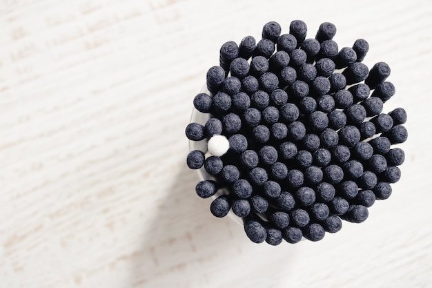 Bastoncini di cotone neri con un singolo bastoncino di cotone bianco tra loro visti dall'alto. Concetto di diversità