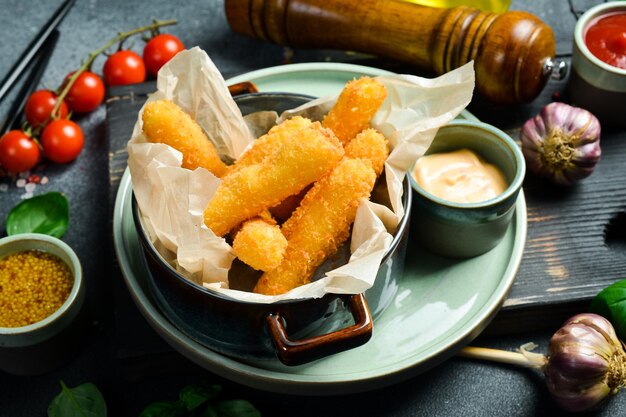 Bastoncini di formaggio fritto con salsa burger vicino su un piatto su uno sfondo di pietra nera