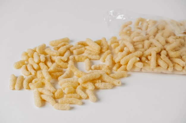 Bastoncini di mais in un sacchetto di plastica sparsi su uno sfondo bianco. Vista dall'alto. Copia, spazio vuoto per il testo