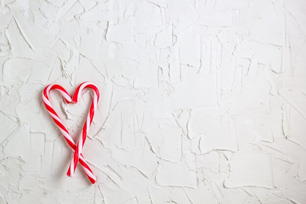 Bastoncini di zucchero di Natale a forma di cuore su fondo bianco