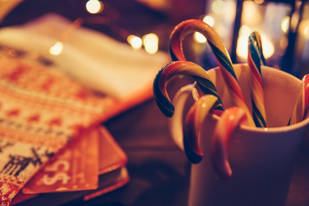 Bastoncini di zucchero in una tazza sul fondo vago delle luci di Natale