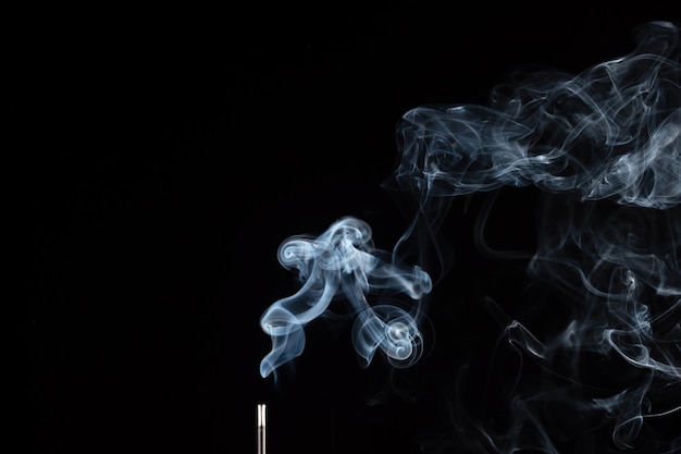 Bastoncino di incenso con fumo su sfondo nero