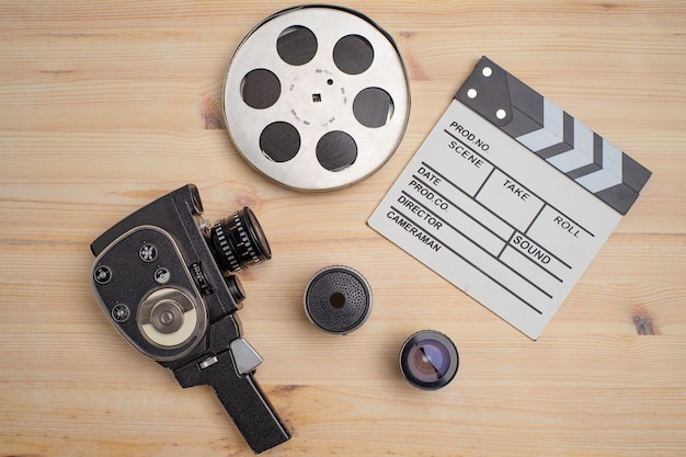 Batacchio di film, bobina di film e macchina fotografica su fondo di legno, vista dall'alto