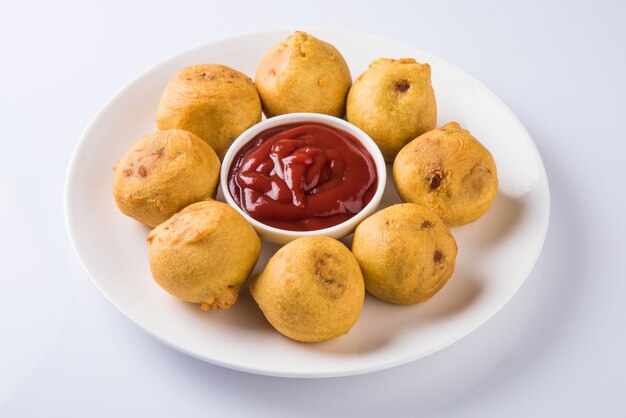 Batata Vada o Aloo Bonda è un gustoso e popolare snack indiano per l'ora del tè servito con peperoncini verdi e ketchup di pomodoro. Messa a fuoco selettiva