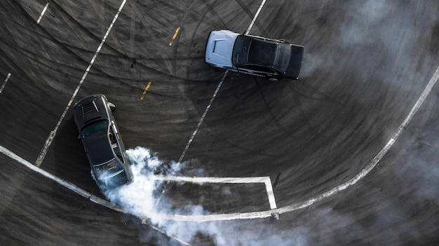 Battaglia di deriva aerea vista, due auto deriva battaglia su pista con fumo.