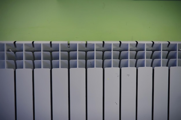 Batteria del radiatore in alluminio moderno bianco per il riscaldamento dell'acqua calda sullo sfondo di una parete all'interno di un appartamento o di uno spazio ufficio