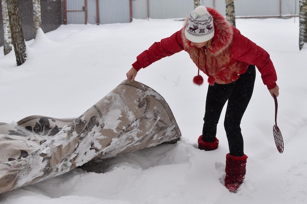 Batti il tappeto dalla polvere in inverno sulla neve. pulire i tappeti di casa con la neve. il tappeto giace sulla neve bianca