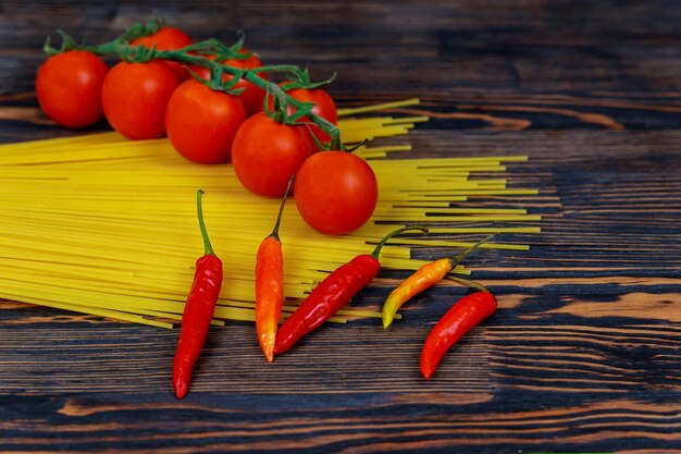 Bavette crude degli spaghetti con i pomodori, ingredienti del pepe per la cottura della pasta italiana.