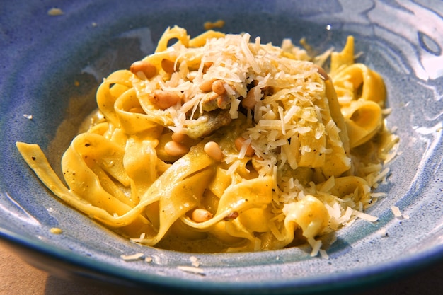 Bavette di pasta con noci aglio olio d'oliva Vista laterale primo piano Pasta con parmigiano Deliziosi spaghetti serviti su un piatto di ceramica blu Cena di pasta Alfredo cremosa salsa bianca Tagliatelle