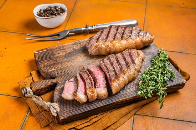 BBQ Arrosto brasiliano Picanha bistecca tazza rump bistecca di carne di manzo su un tavolo da servizio in legno sfondo arancione vista superiore