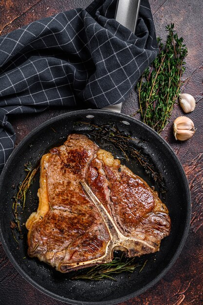 BBQ Bistecca di carne di manzo alla griglia con le erbe su un piatto sulla tavola di legno. Vista dall'alto.