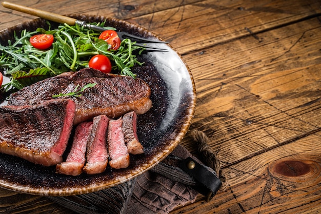 BBQ Bistecca di carne di manzo con scamone alla griglia in piastra con insalata di verdure Sfondo in legno Vista dall'alto Spazio di copia