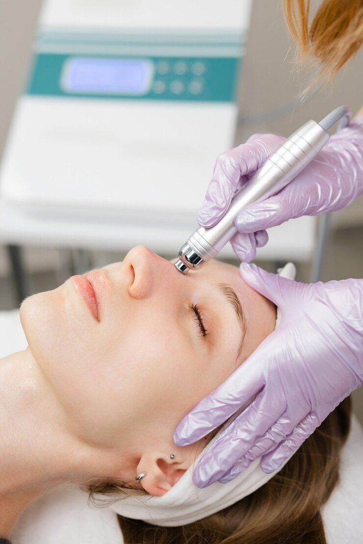 Beautician performing hydradermabrasion treatment on young womans face