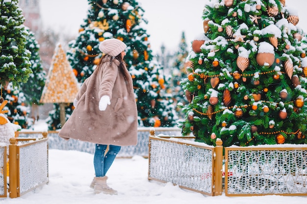 Beautidul donna vicino all'albero di Natale nella neve all'aperto