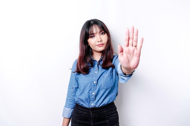 Beautiful Asian woman wearing blue shirt with hand gesture pose of stop or prohibition with copy space