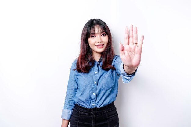 Beautiful Asian woman wearing blue shirt with hand gesture pose of stop or prohibition with copy space